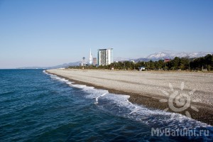 Пляж Батуми в феврале: солнечный день, безлюдный пляж, заснеженные горы вдалеке. Зима в Батуми